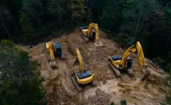 Arial view of 4 excavators on top of a hill, surrounded by a forest thumbnail